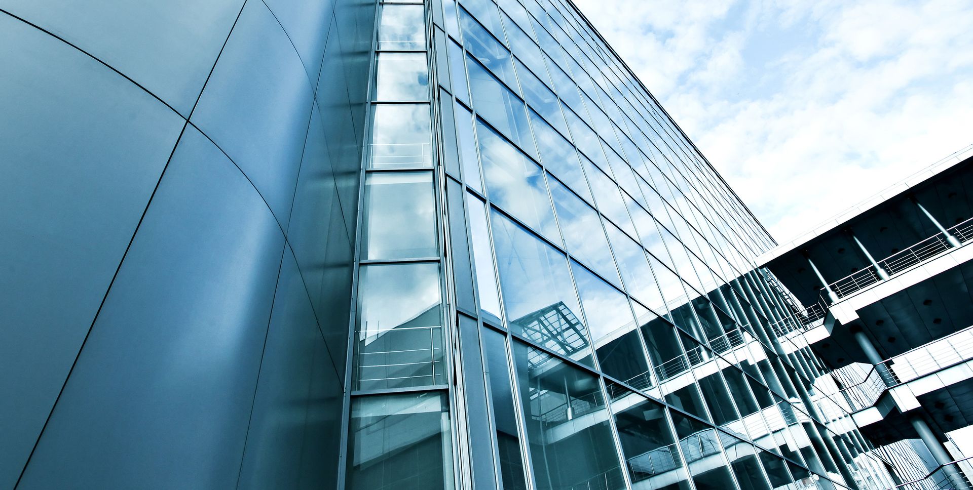 Ein modernes Gebäude mit Glaswänden vor einem klaren Himmel, das Licht und Transparenz ausstrahlt.